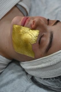 Femme appliquant un masque d'or sur la moitié de son visage
