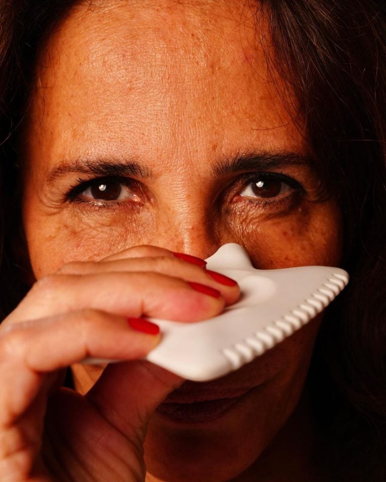 Une femme tient un outil Gua Sha dans sa main